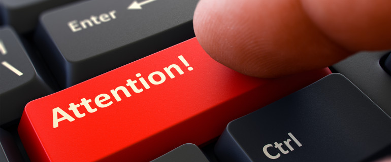 Attention Button. Male Finger Clicks on Red Button on Black Keyboard. Closeup View. Blurred Background.