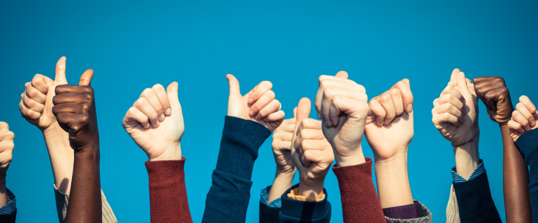 Multiracial Thumbs Up Against Blue Sky
